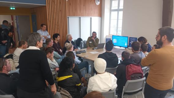 Visuel d'un atelier de médiation sur les IA génératives de texte où l'on voit les participants assis autour d'une table sur laquelle un écran servant de support d'échange et de présentation est posé.