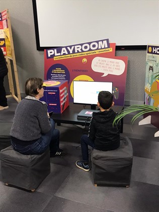 Un enfant et une adulte devant un jeu vidéo permettant de "faire l'expérience d'une émotion"